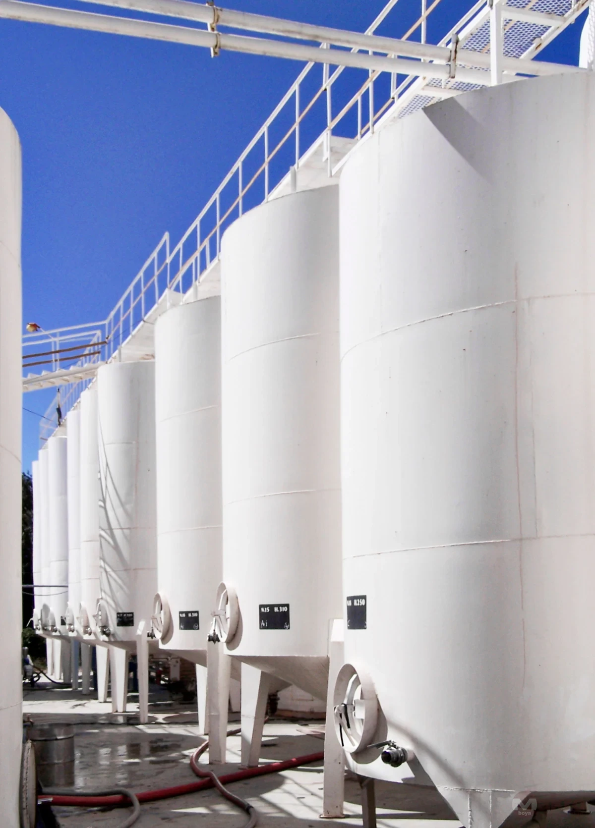 Açık alanda yan yana dizilmiş beyaz endüstriyel metal tanklar